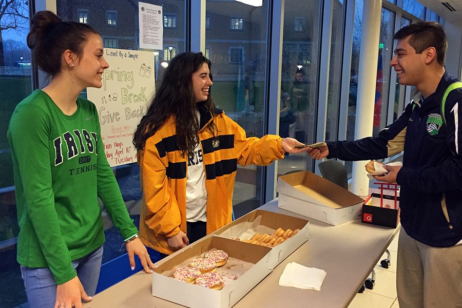 Juniors Anna Mattingly and Mary Ann McGinley sell donuts to senior Max Eslava before school on March 31 to fund this year’s prom.