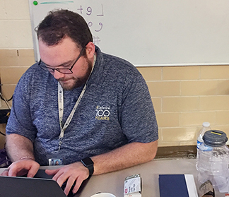 Theology teacher Mr. Matt Cannaday works at his desk in his classroom on the first floor of Kelly Hall. In June, Cannaday will travel to Peru to help lead 13 students on a mission trip. 