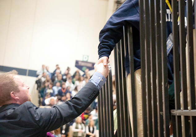 Vice Principal Mr. Jere Kubuske shakes the hand of a lanyard-wearing freshman at Winterfest. 