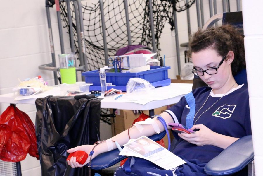 During one of the blood drives that took place earlier this school year, senior Avaleen Sweeney checks her phone as she makes her donation. The third blood drive of the school year will take place April 15 in the Welch Activity Center. 