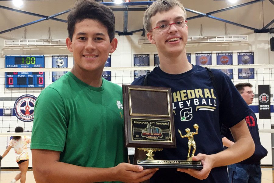 Senior Andrew George, right, shows off the womens volleyball City championship trophy. 