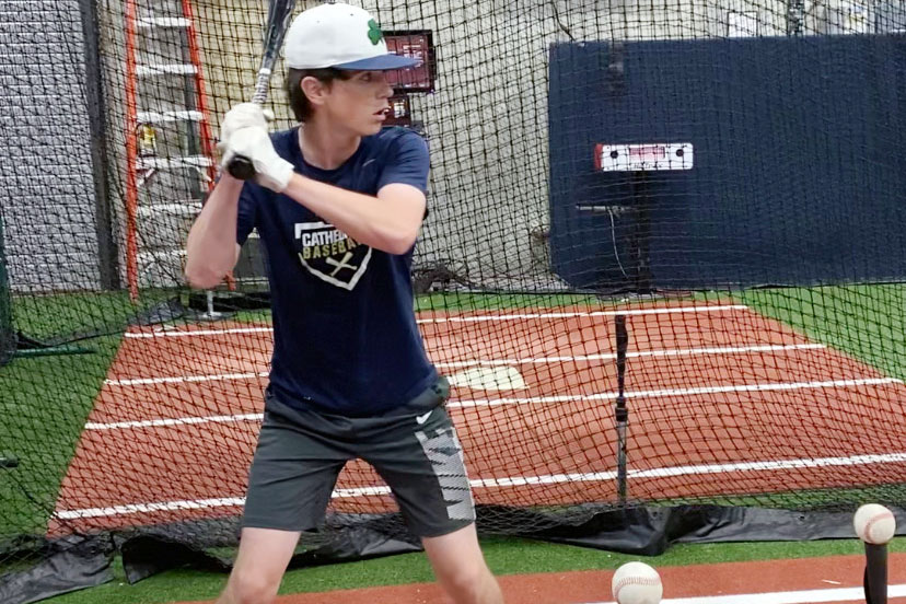 At the Indiana Baseball Academy in Westfield, junior Will Mayer prepares to hit off a tee. The Hit Trax machine in the background, similar to a golf simulator, will record and break down every element of his swing, helping him to improve his game. 
