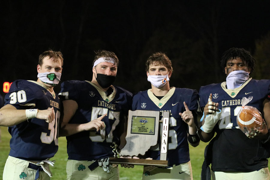 Varsity football players show off the Sectional championship trophy. 