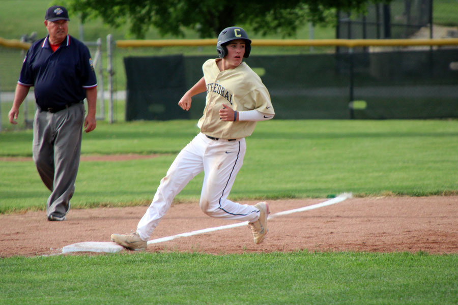 As the umpire looks on, senior Andrew Davey prepares to round third base during the varsity baseball teams 21-3 win over Crispus Attucks on the Sectional opener. 