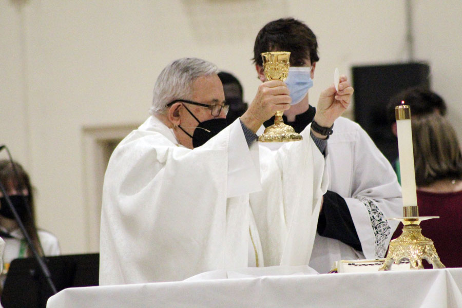 Fr. Jeff Godecker and senior Will Mayer prepare the table for the Eucharist.