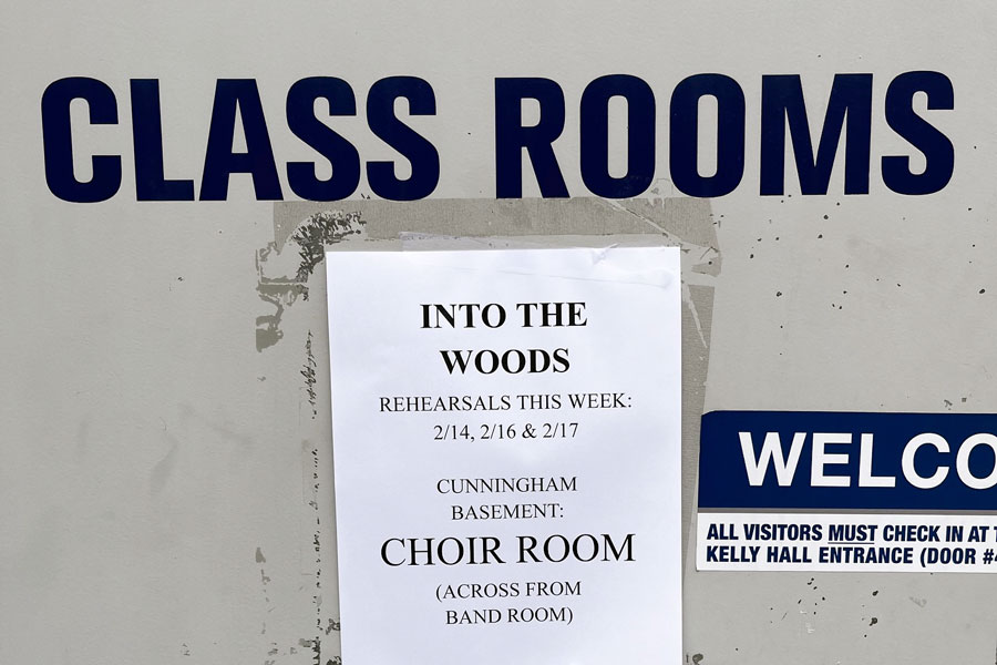 A sign outside the theater classrooms provides information about In the Woods rehearsals.