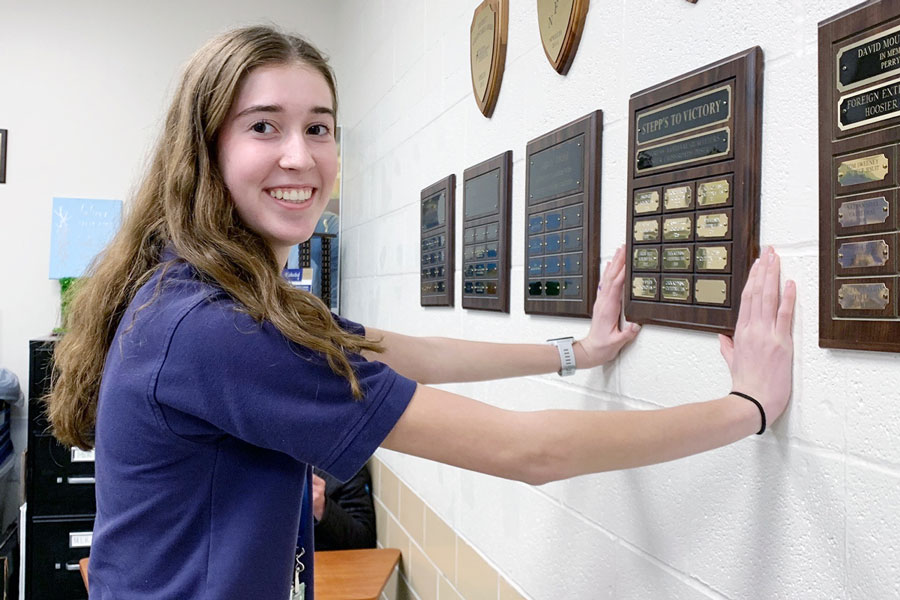 Junior Madeline Taylor hangs the traveling plaque commemorating her victory in the qualifying rounds of Congressional debate.