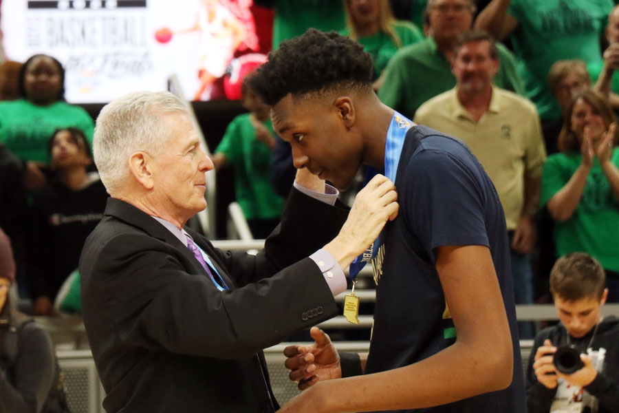 Mr. Dave Worland presents junior Xavier Booker with the Class 4A State champion medal. 