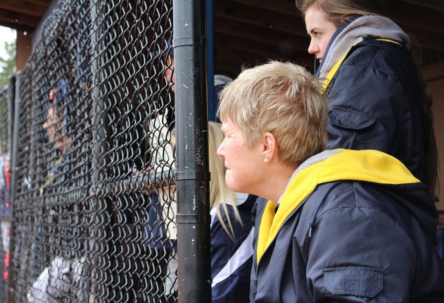 Physical education department chair and varsity softball assistant coach Mrs. Linda Bamrick takes in the action from the dugout. 