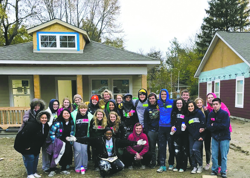 Seniors and teacher chaperones pose in front of the houses worked on through Habitat for Humanity on Nov. 9. Throughout the year, seniors have voluteered their time on the  site to construct a home.
