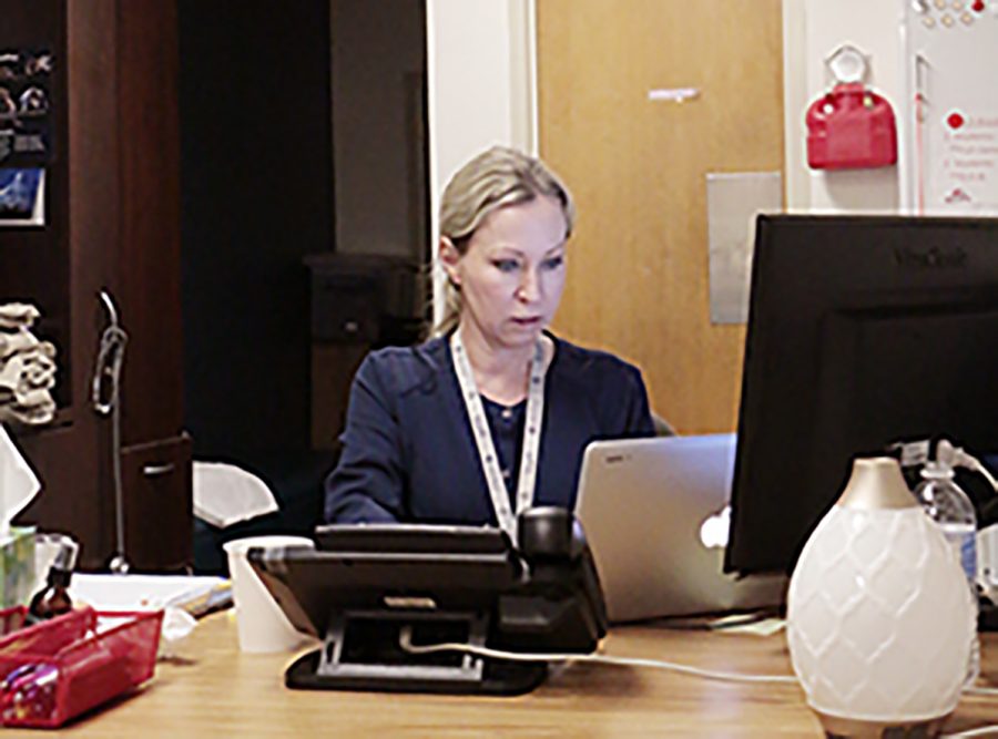 Nurse Mrs. Courtney Jennings-Sood works at her computer in her office on the first floor of Kelly Hall.