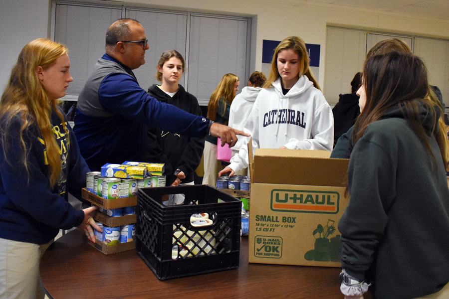 Theology teacher Mr. Ed Freije '99 points out where students should leave their donations for this year's canned food drive. 