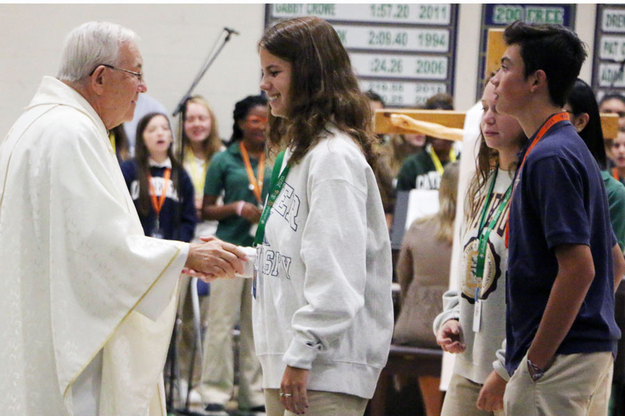 During a Mass earlier this school year, Fr. Jeff Godecker greets senior Lila Welch. 