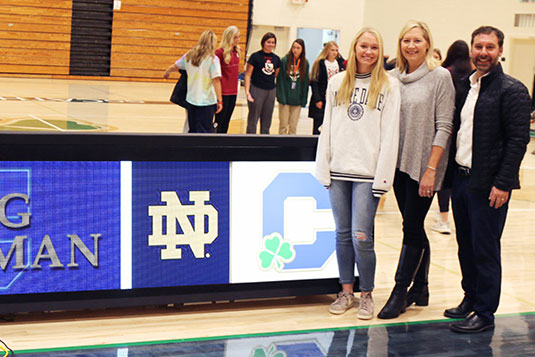 Senior Megan Coleman stands with her parents during the fall signing ceremony, which recognized seniors who had signed a commitment letter to their university. 