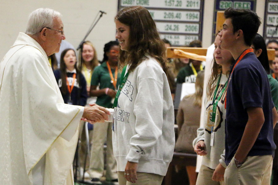 Fr. Jeff Godecker greets senior Lila Welch at Mass earlier this school year. Fr. Godecker celebrated Easter Mass in the school chapel, and that Mass was live streamed through the school's Facebook page. 