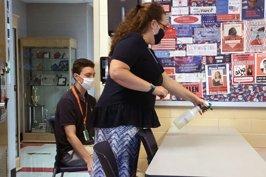 Social studies teacher Mrs. Jill Twilleager sprays disinfectant on a desk in her classroom during period F on Sept. 8. 