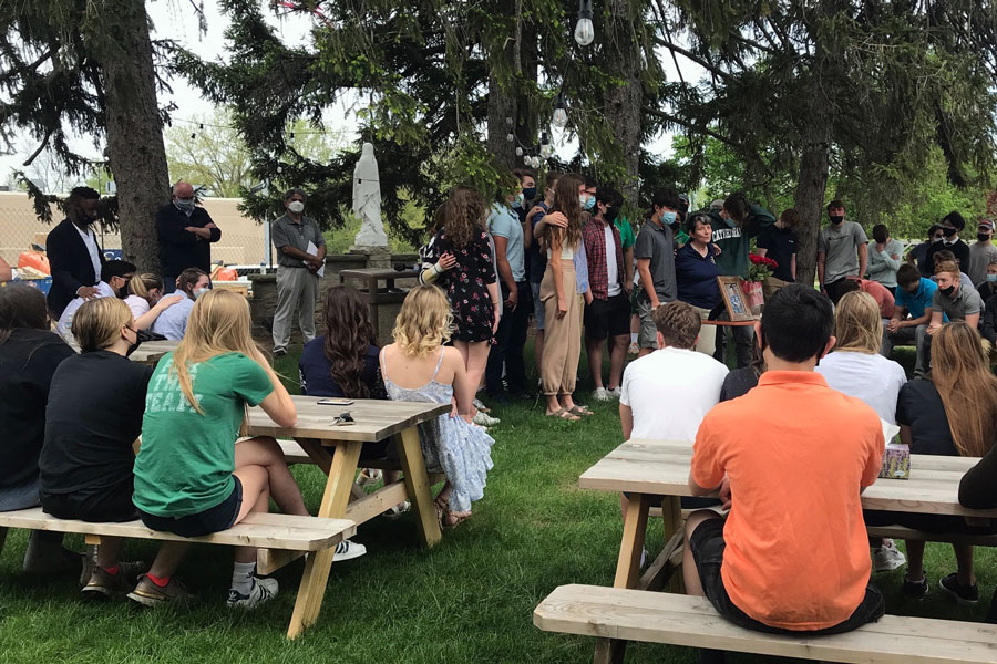 Surrounded by members of the speech and debate team, their coach, Mrs. Jeanne Malone, addresses the students who gathered on campus on May 2 to mourn the passing of junior Lendon Byram. 