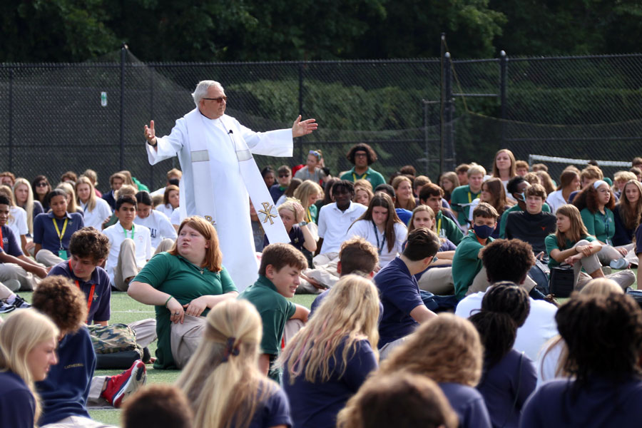 Fr. Jeff Godecker walks among students on the football field during the first Mass of the school year. Mass also will be celebrated on Sept. 15. 