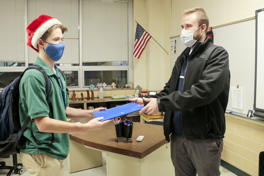 Junior Nick Busam turns in forms to Mr. Cole Hepp ahead of time for the Canadian pilgrimage course that will take place during the upcoming J-Term. Students are required to turn in money along with a folder of contact information and other important documents to either Br. Roberto Jimenez or Hepp