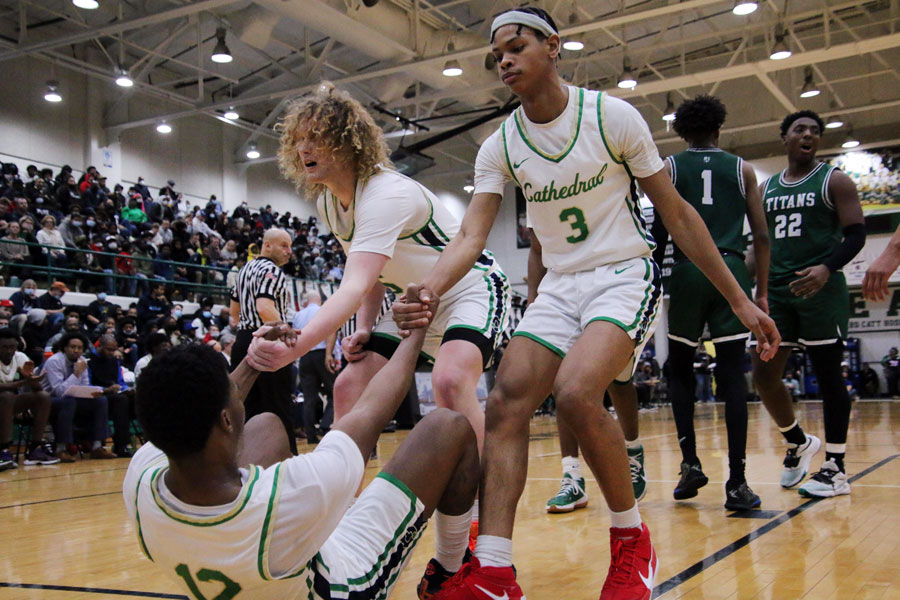 During the City championship game, Jake Davis (left) and Sincere Germany assist their teammate, Tayshawn Comer. The Irish won the title game over Tech 80-64. 