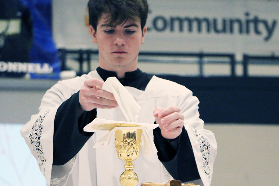 Senior Will Mayer assists at the altar at a Mass earlier during this school year. Mayer will be an altar server at the Ash Wednesday Mass on March 2.